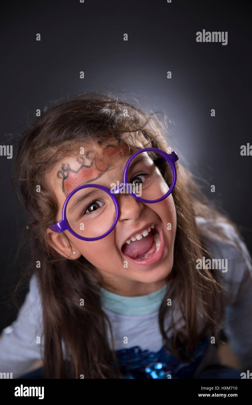Portrait of a funny four years girl with glasses and makeup making