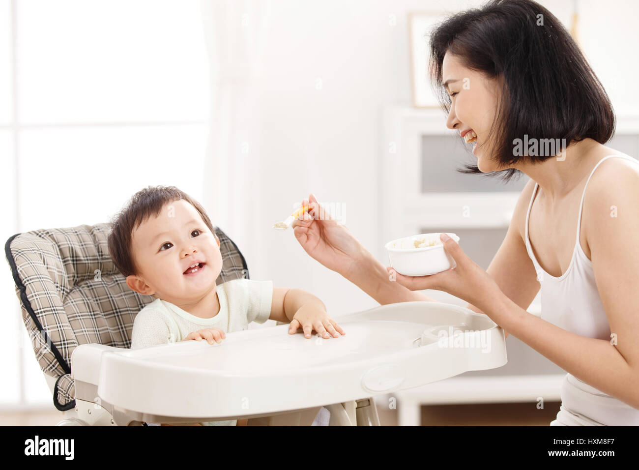 Mother feeding baby in high chair Stock Photo Alamy