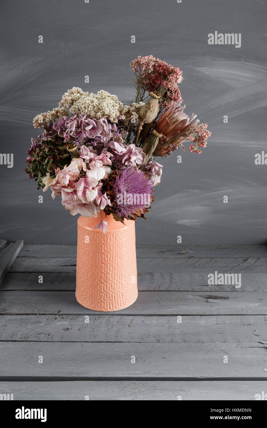 Still life image of dried flowers in rustic vase against weathered ...