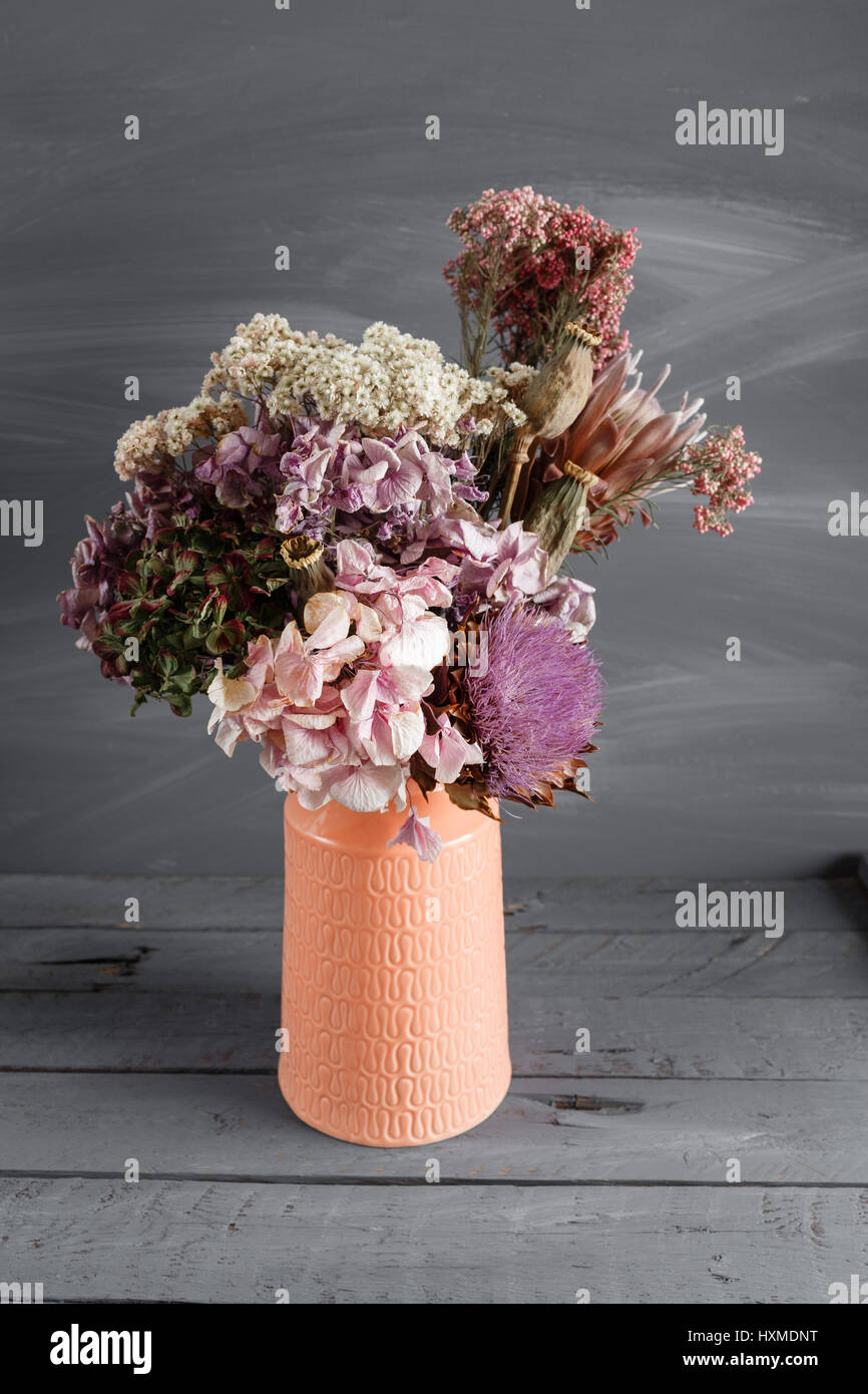 Still life image of dried flowers in rustic vase against weathered ...