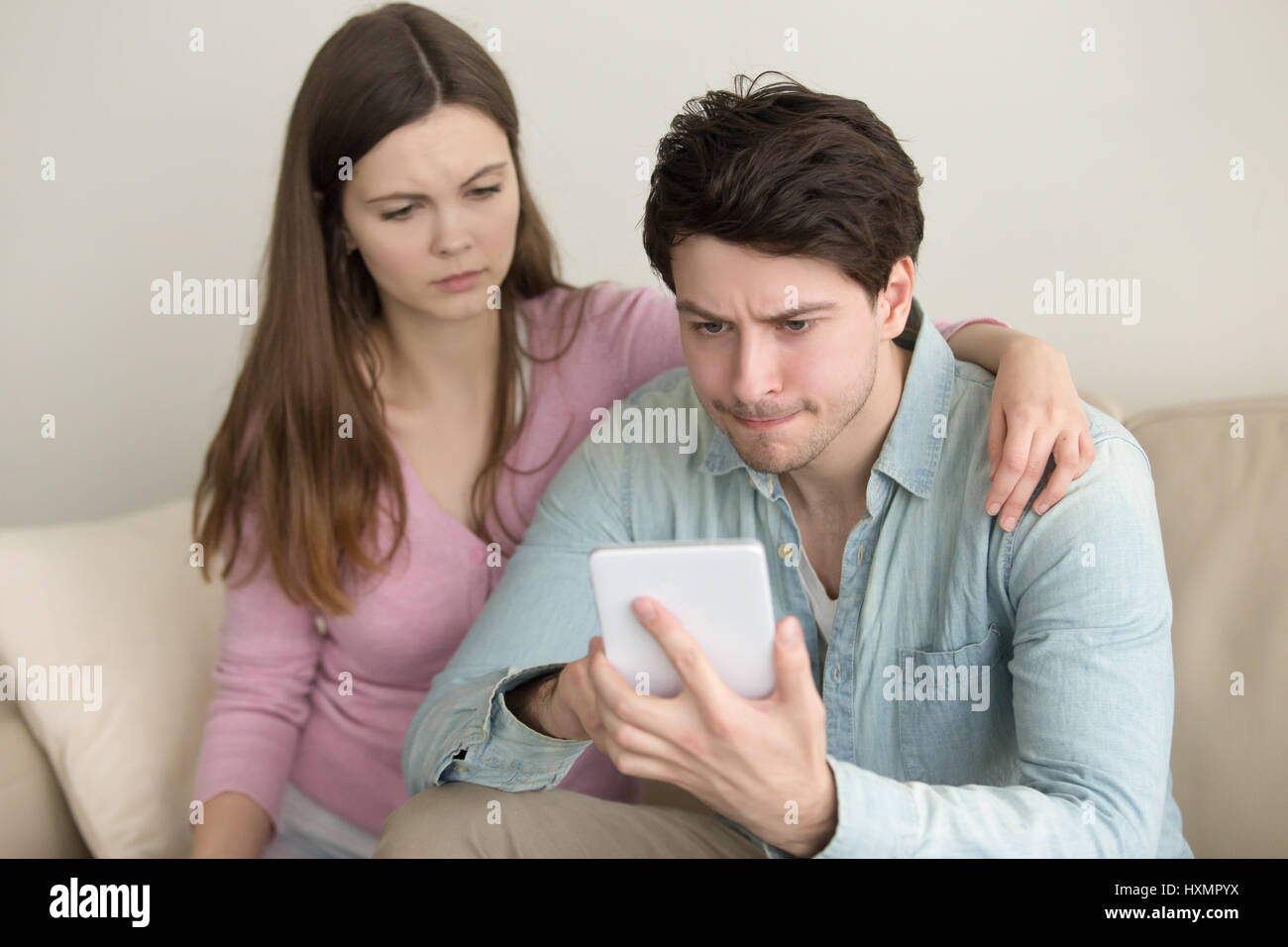Young man using tablet, having problems, girlfriend anxious and  Stock Photo