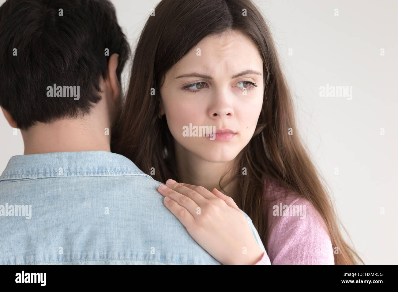 Attractive young woman embracing man, girl looking serious and w Stock Photo