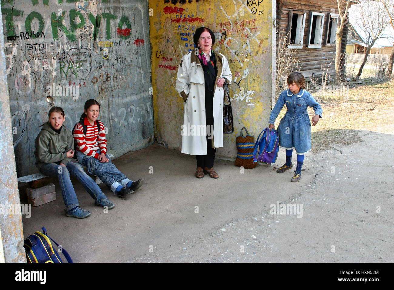 Tver, Russia - May 2, 2006: Rural schoolgirls and their teacher, expect transport at the bus stop Stock Photo