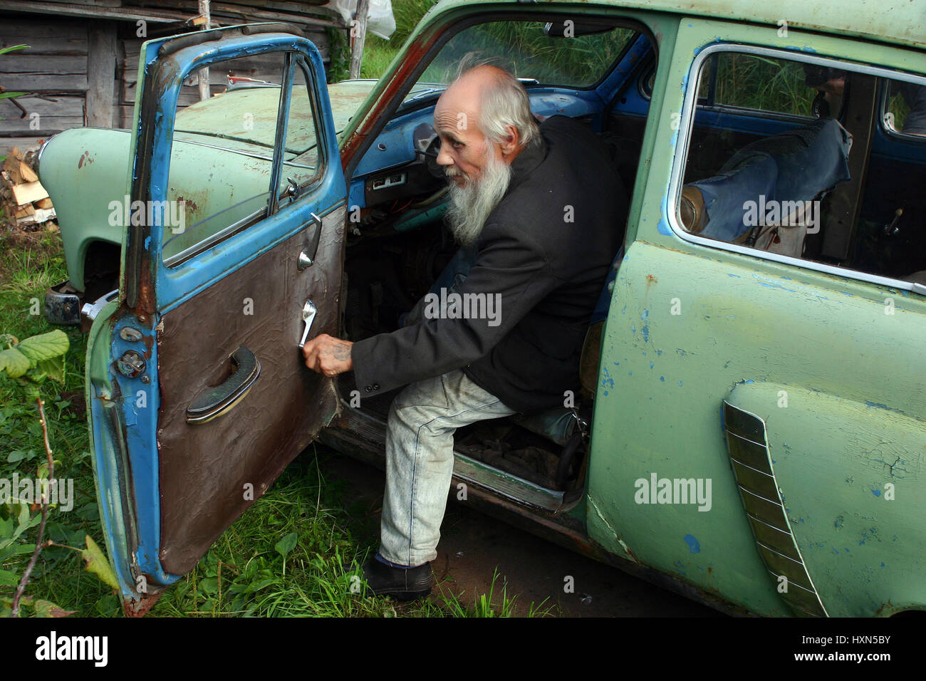 Leningrad area of St. Petersburg, Russia - August 23, 2006: Valentin Stepanovich Shramko born in 1938, Elderly man sits in an old Soviet-made car, Mos Stock Photo