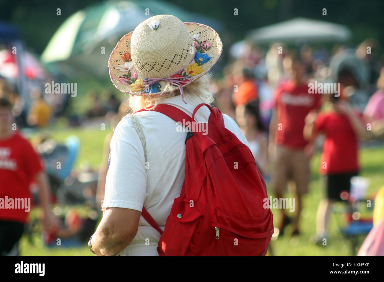 Woman with hat and backpack at outdoor event Stock Photo