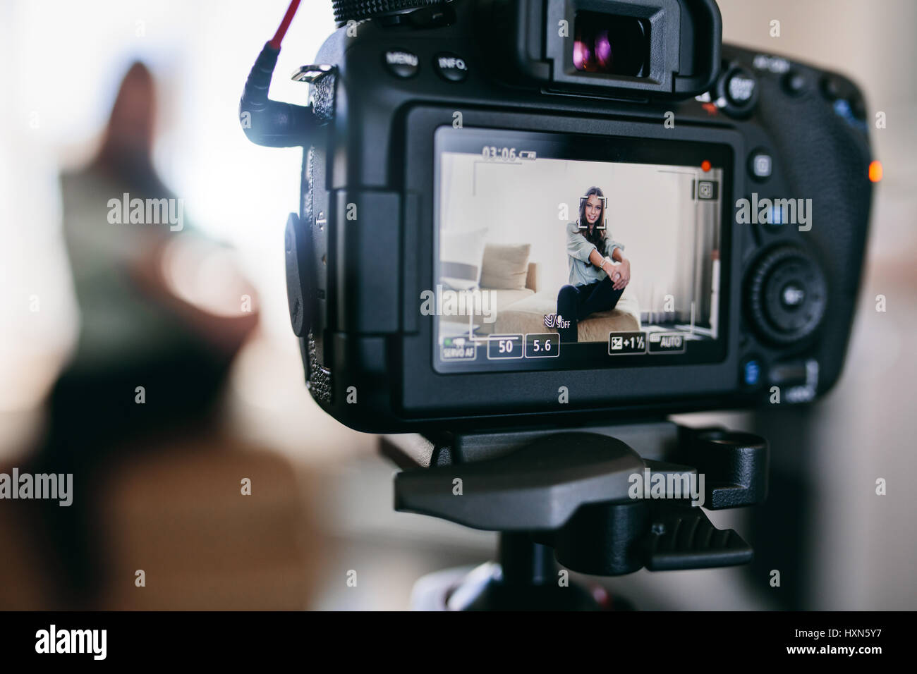 Young female vlogger recording content for her vlog sitting in her living room. Closeup of camera screen showing a young girl recording video blog. Stock Photo