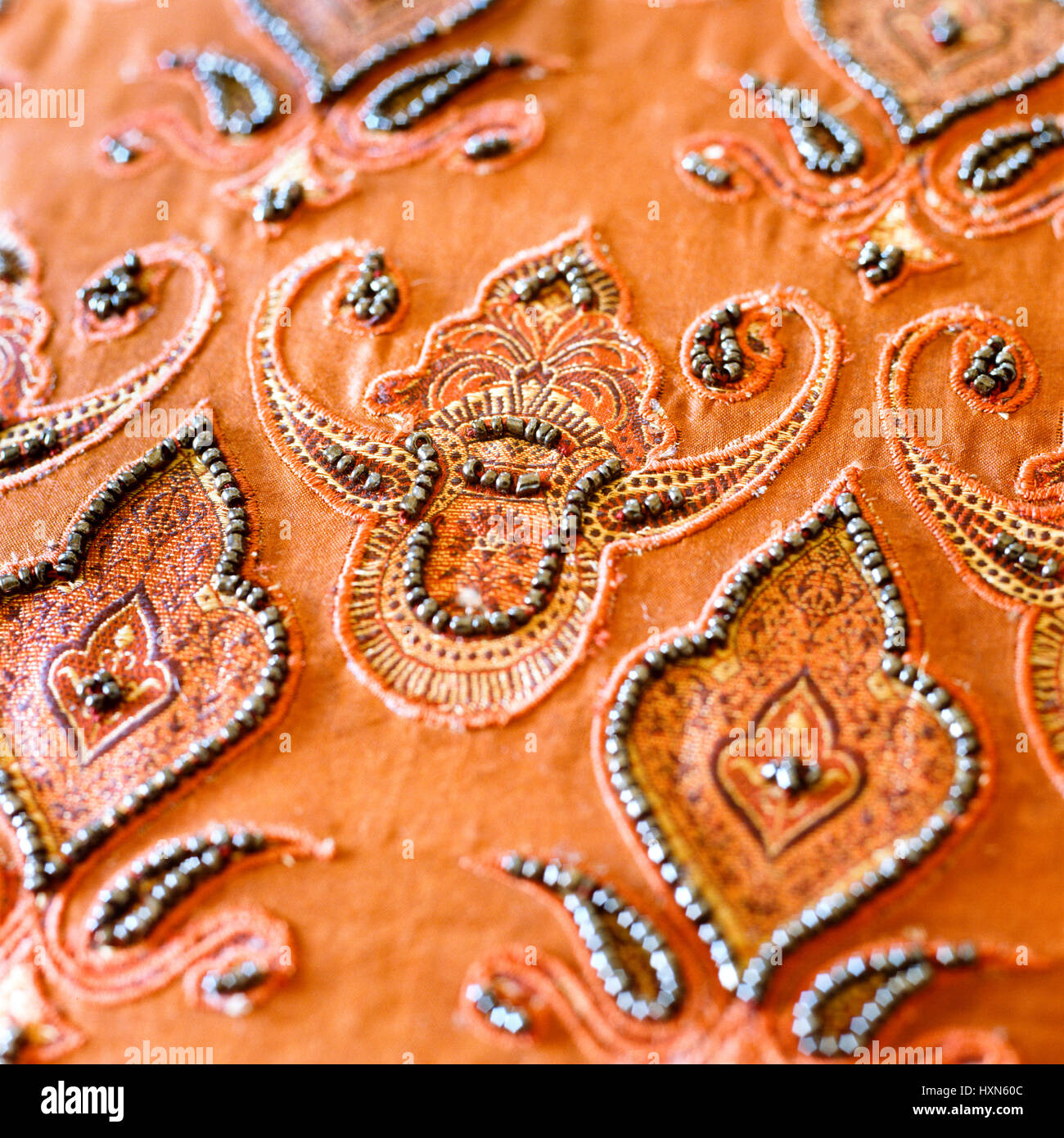 Bead detailing on orange fabric. Stock Photo