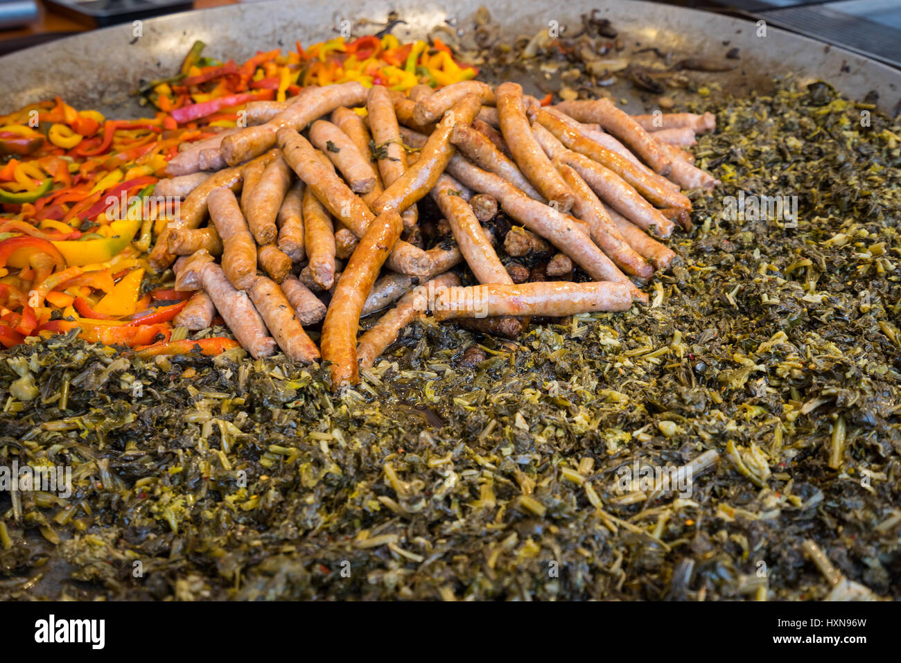 Typical dish of Puglia with sausage, turnip top and peppers, prepared in a large pot during a food fair Stock Photo