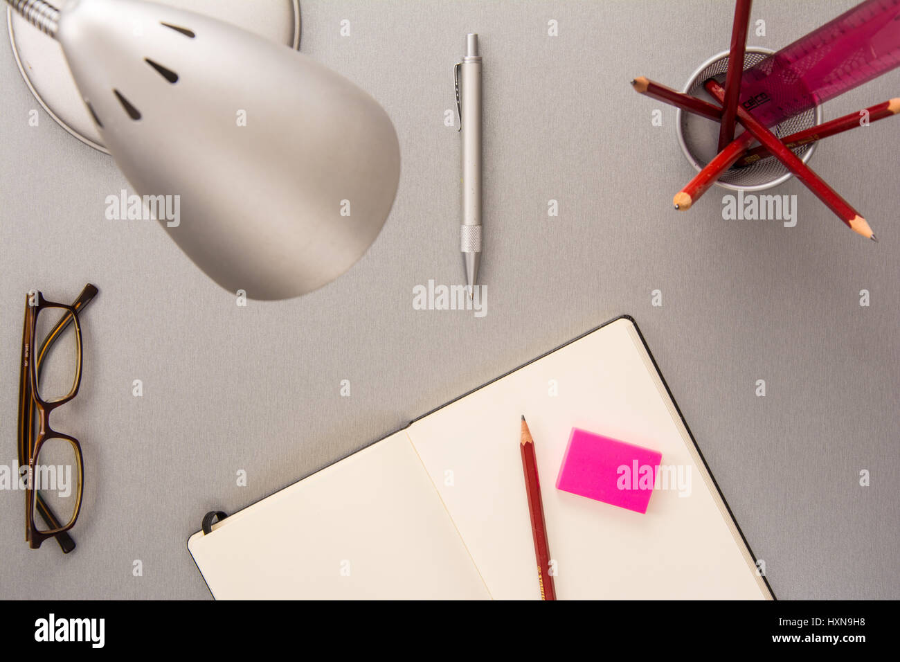 High angle view of a collection of desk elements such as pencils, notebook, lamp, eyeglasses, pen and eraser in a modern style Stock Photo