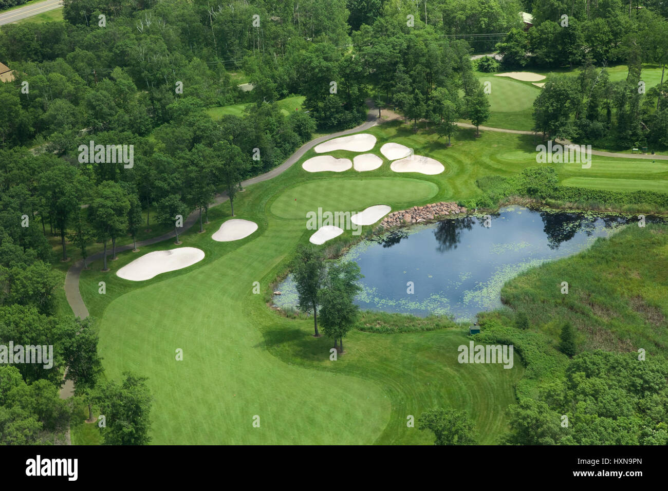 Aerial view of golf course fairway and green with sand traps, pond and trees Stock Photo