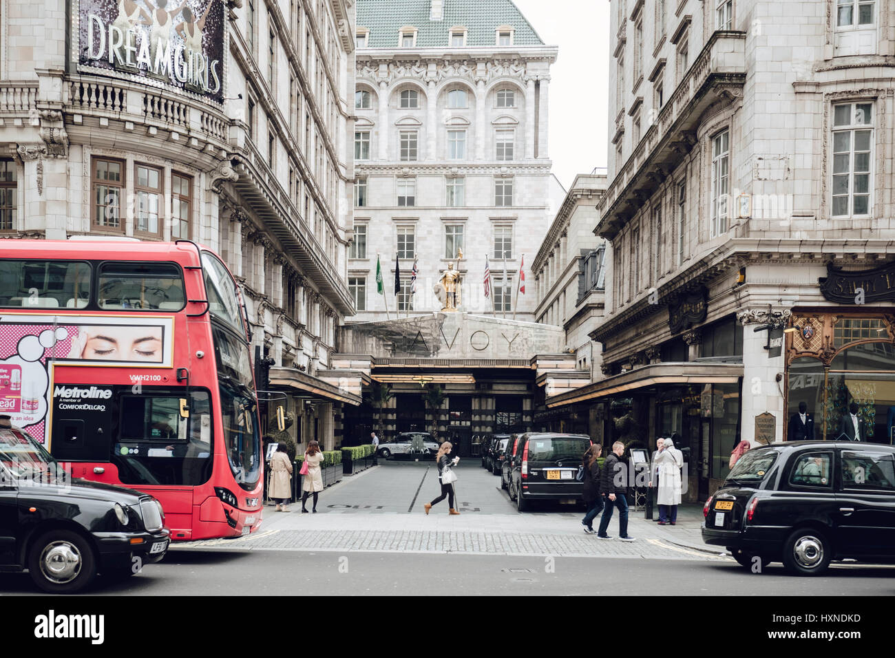 The Savoy Hotel, the Strand, London from the street. London buses, walkers and black taxis