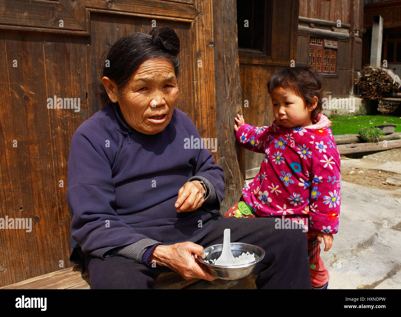 GUIZHOU PROVINCE; CHINA - APRIL 8: Dong ethnic old woman feeds child of three years by house in Zhaoxing Dong Village, April 8; 2010. Liping County. G Stock Photo