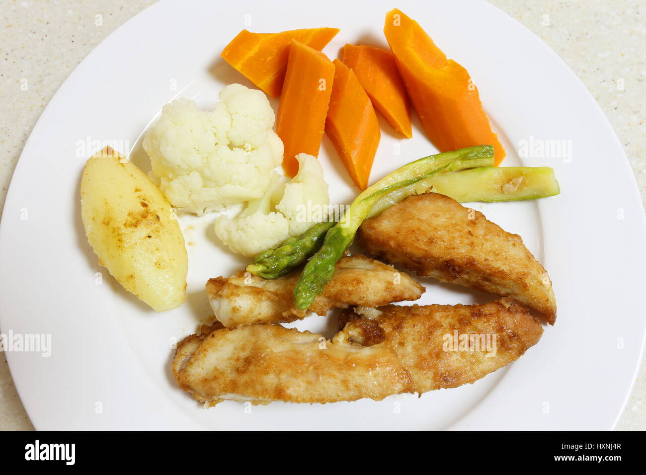 Pan fried chicken breast, coated with seasoned flour and served with asparagus and steamed vegetables Stock Photo