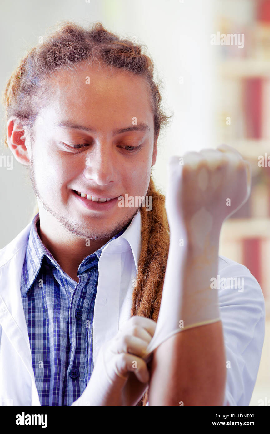 Young doctor with long dread locks posing for camera while putting on