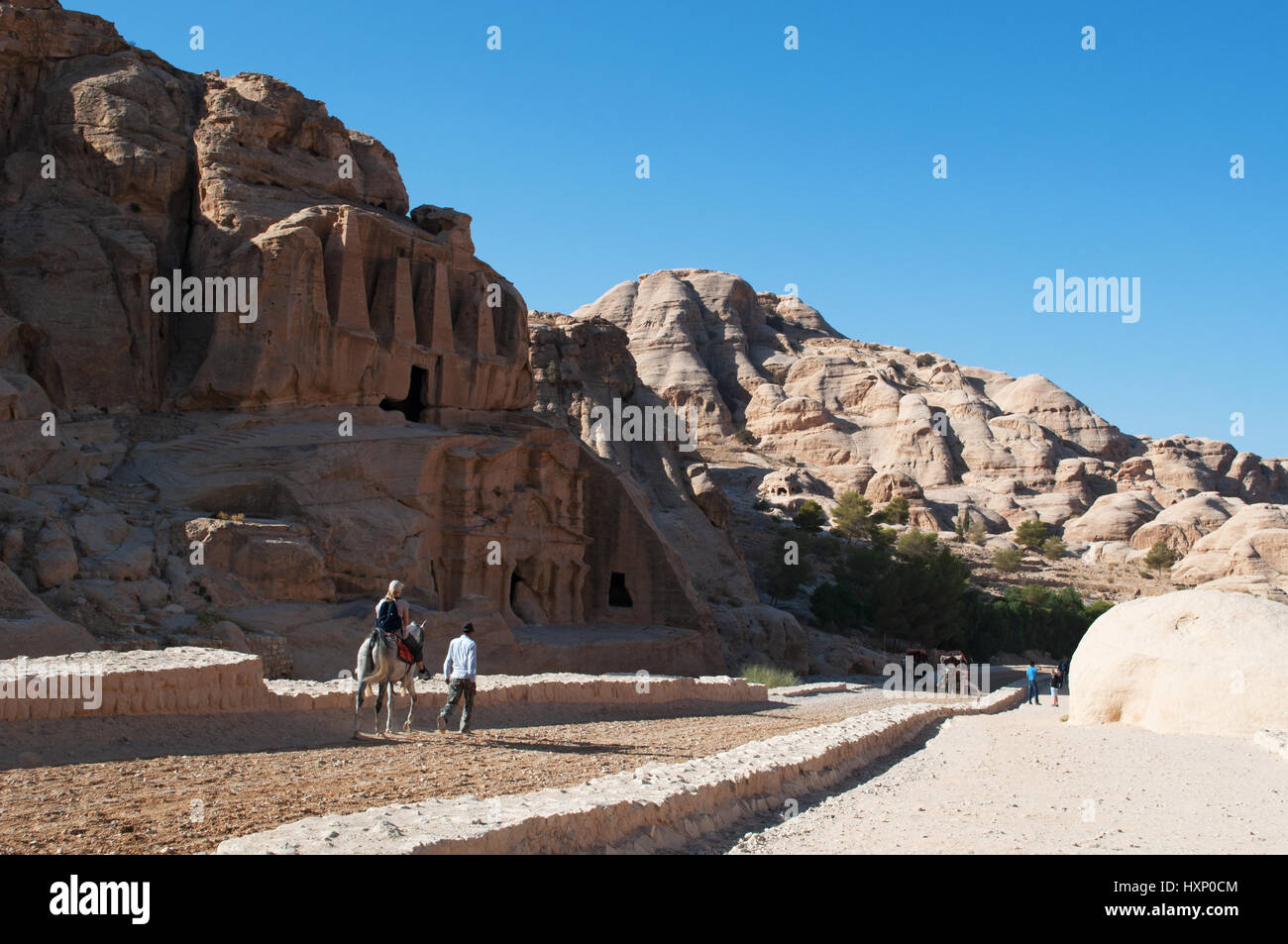 Jordan: a tourist on a donkey in front of the Obelisk Tomb and Bab As-Siq Triclinium on the road to the Siq, the main entrance to the city of Petra Stock Photo