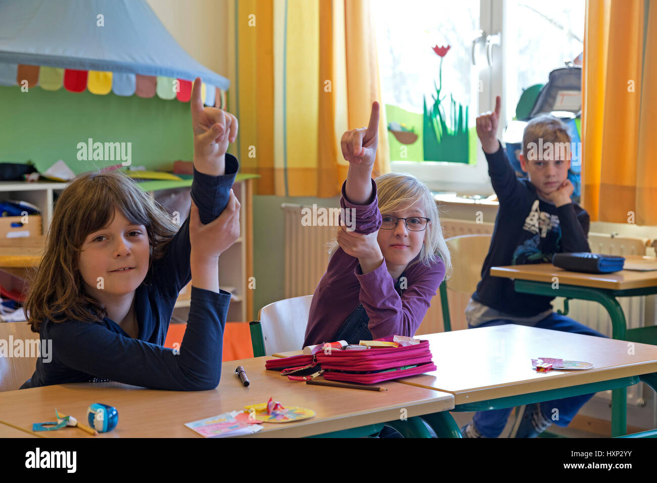 children raising their hands at primary school Stock Photo