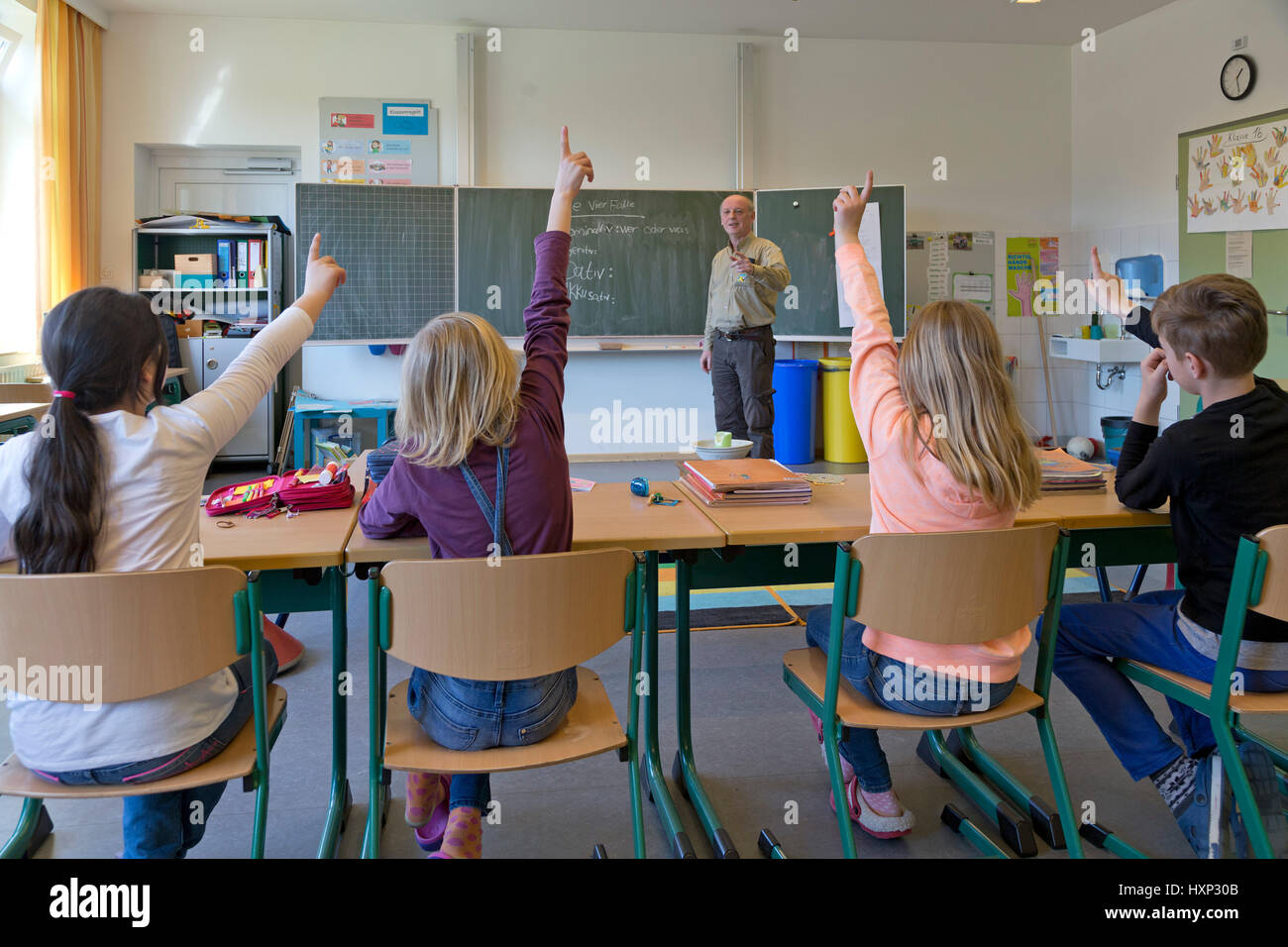 children raising their hands at primary school Stock Photo