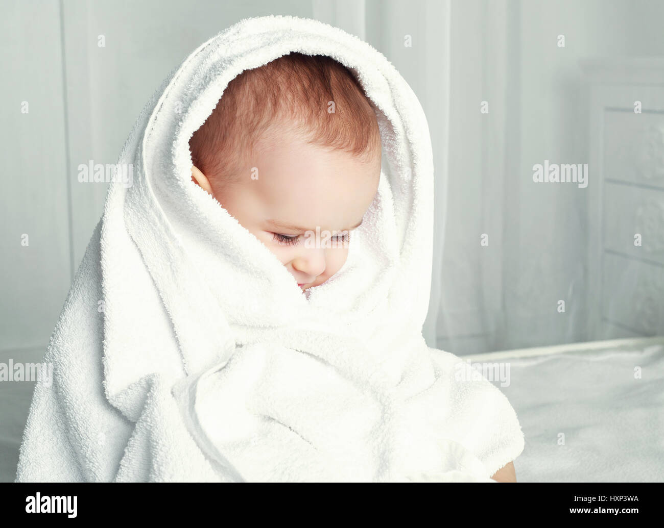 happy one year old baby wearing diapers with a towel in bed at home