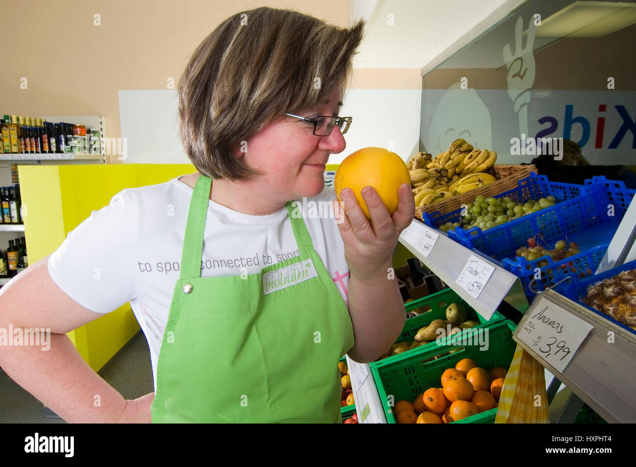 Retail trade shop assistant smells in fruit (mr), Einzelhandelsverkäuferin riecht an Frucht (mr) Stock Photo