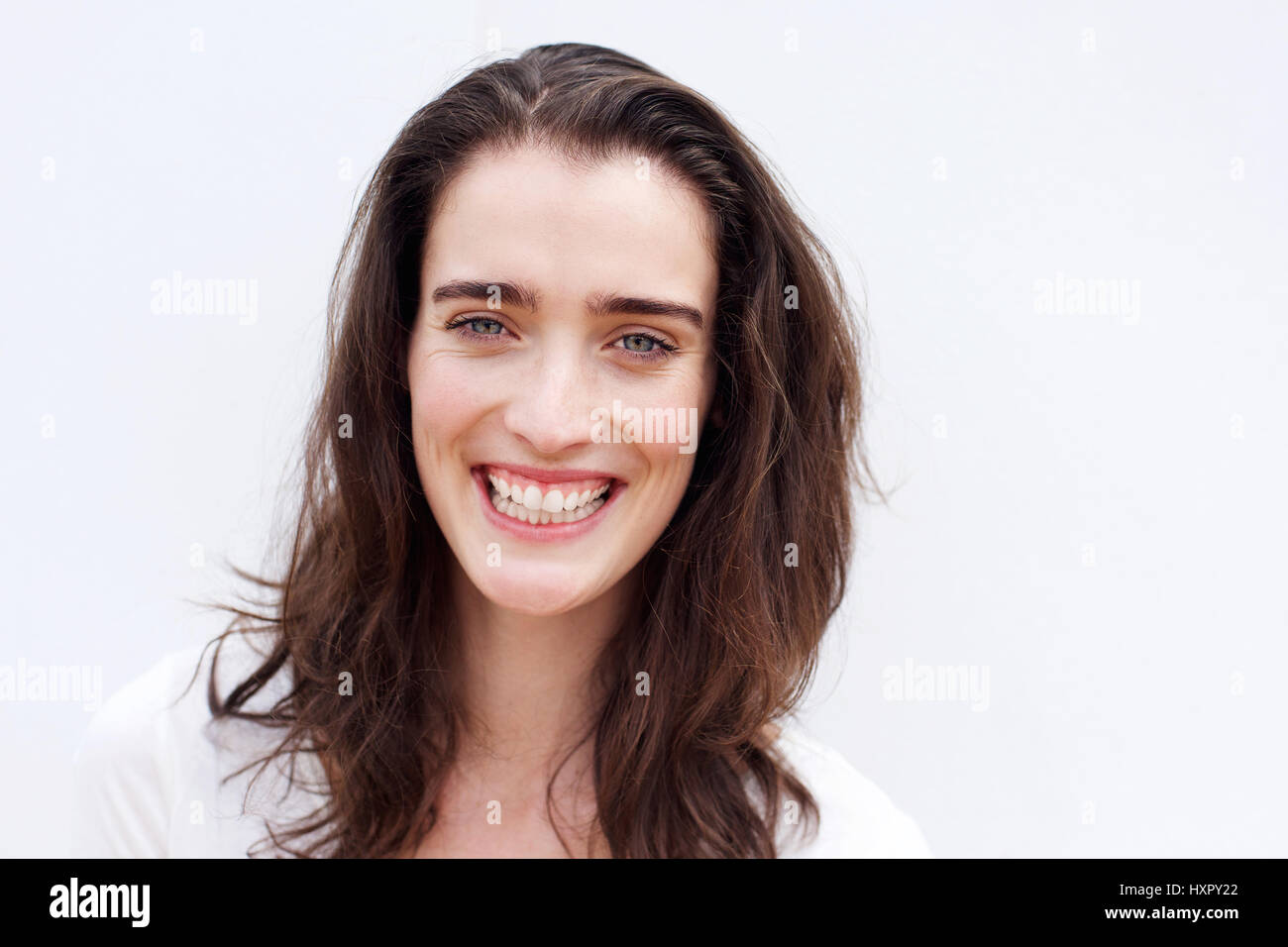 Close up portrait of a cheerful young woman smiling against white ...
