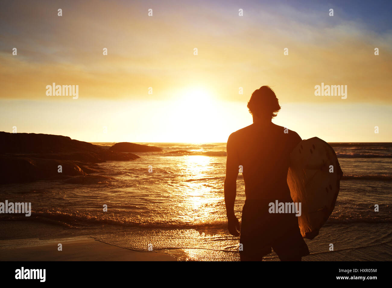 Silhouette of male surfer watching the sunset at the beach Stock Photo ...