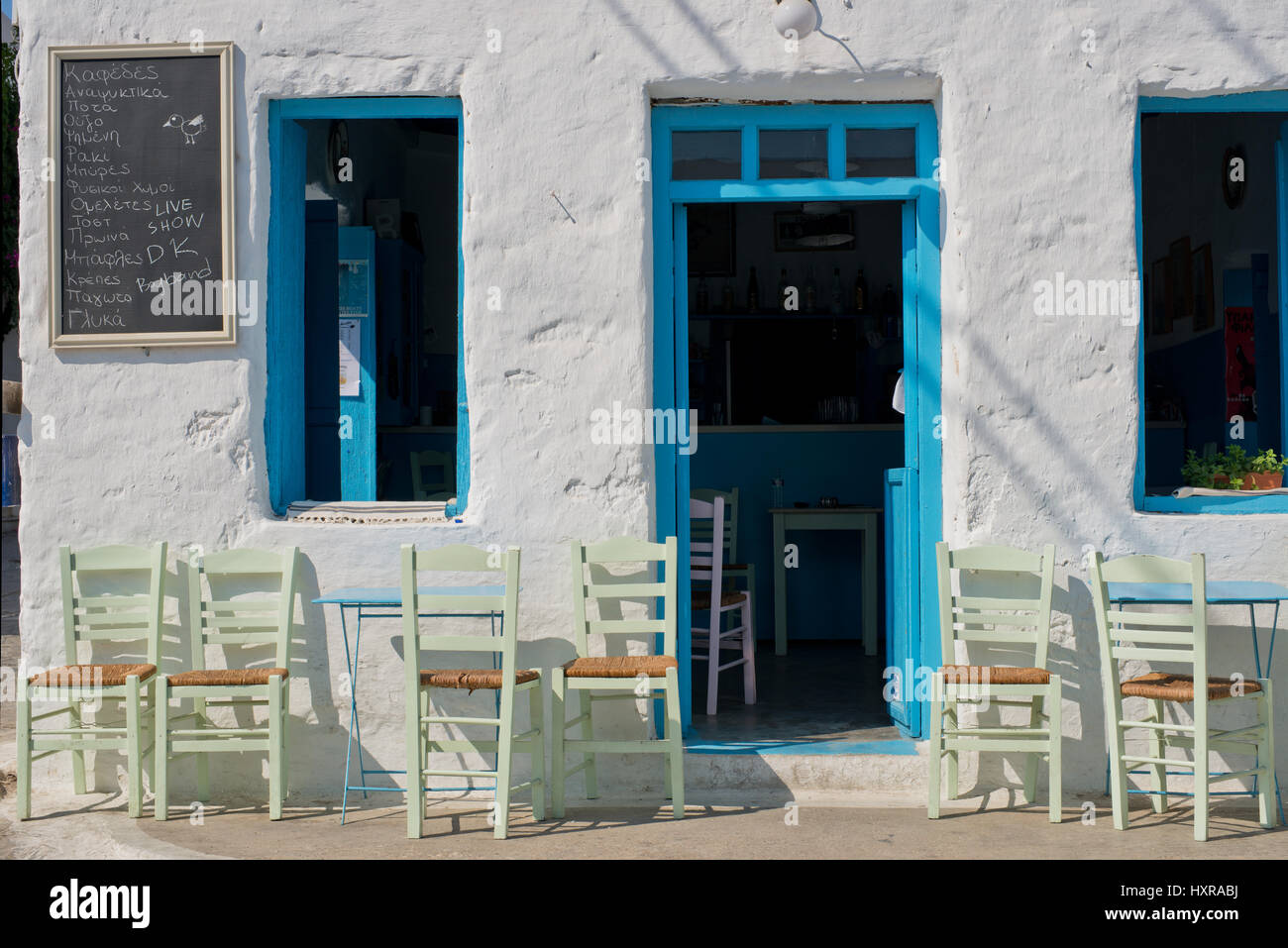 Coffee house, Cafeneion with blue door and windows and green chairs in Schinoussa island at noon time, Cyclades, Greece Stock Photo