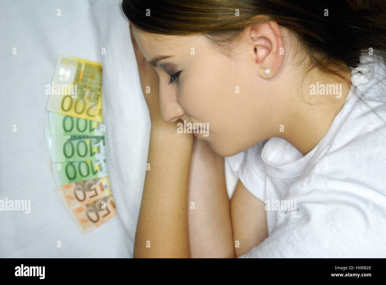 Economic crisis - woman sleeps with cash under the pillow, Wirtschaftskrise - Frau schläft mit Bargeld unter dem Kopfkissen Stock Photo