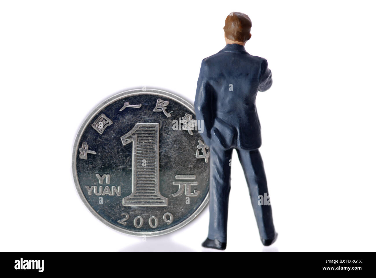 Miniature figure of a businessman before an one-yuan coin (Chinese currency), Miniaturfigur eines Geschäftsmannes vor einer Ein-Yuan-Münze (chinesisch Stock Photo