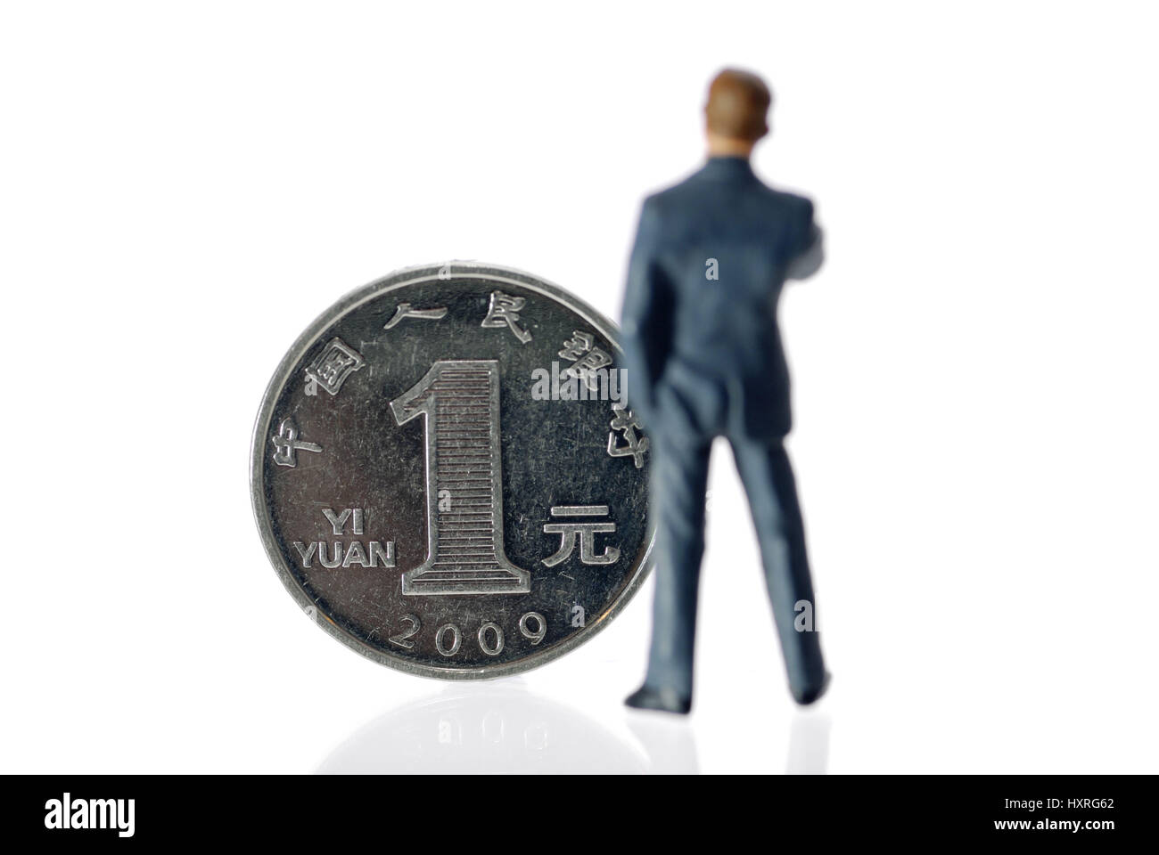 Miniature figure of a businessman before an one-yuan coin (Chinese currency), Miniaturfigur eines Geschäftsmannes vor einer Ein-Yuan-Münze (chinesisch Stock Photo