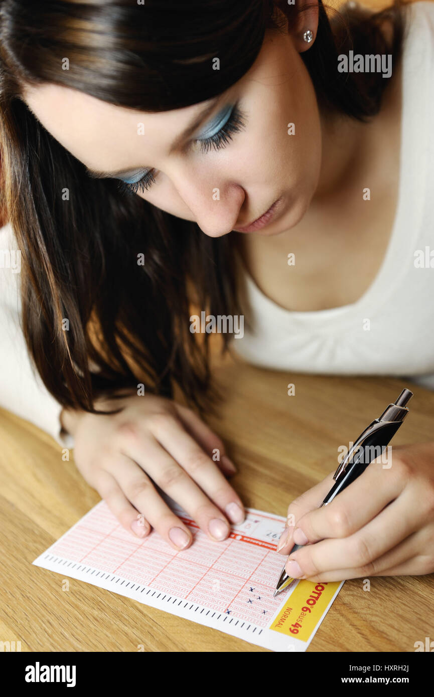 Young woman while filling a lottery coupon, Junge Frau beim Ausfüllen eines Lottoscheins Stock Photo