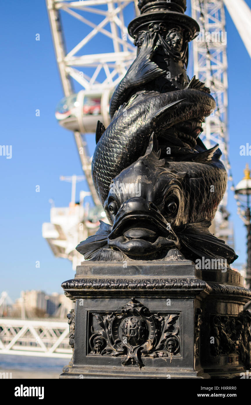 A close up of a fish decorated lamppost on the Thames embankment, London U.K. with the London eye in the background. Stock Photo