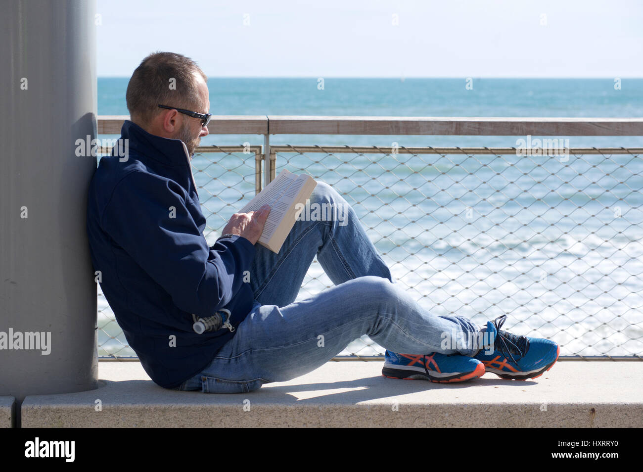 Man reading book at the seaside Stock Photo