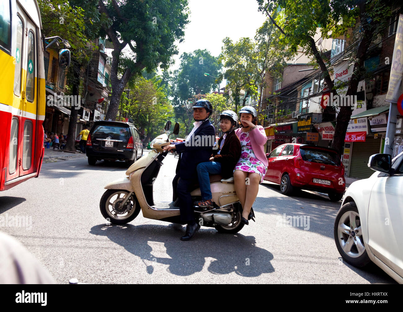 Family on motor bike negotiates through traffic in Hanoi Stock Photo