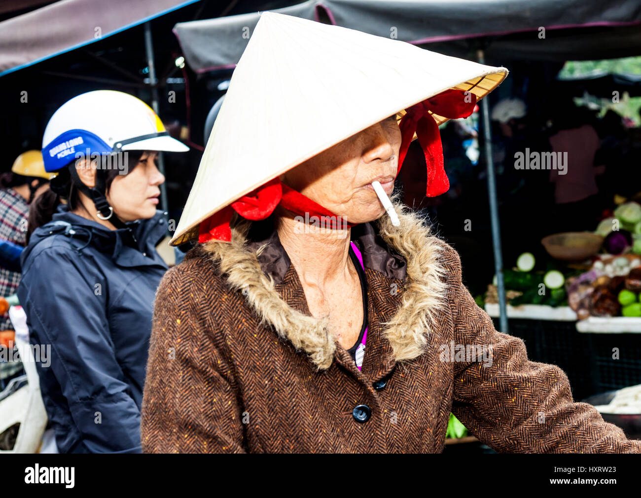 Two Vietnamese woman riding motor bike to market in the rain at Hoi An Stock Photo