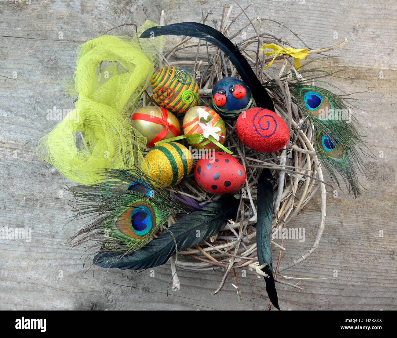 Decorative Easter eggs in nest with feathers on wooden table Stock ...