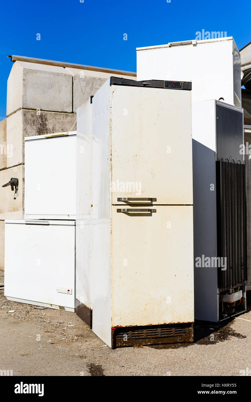 Discarded fridges and freezers at a local waste station. Here they stand in wait for transport to be recycled. Logos removed. Stock Photo