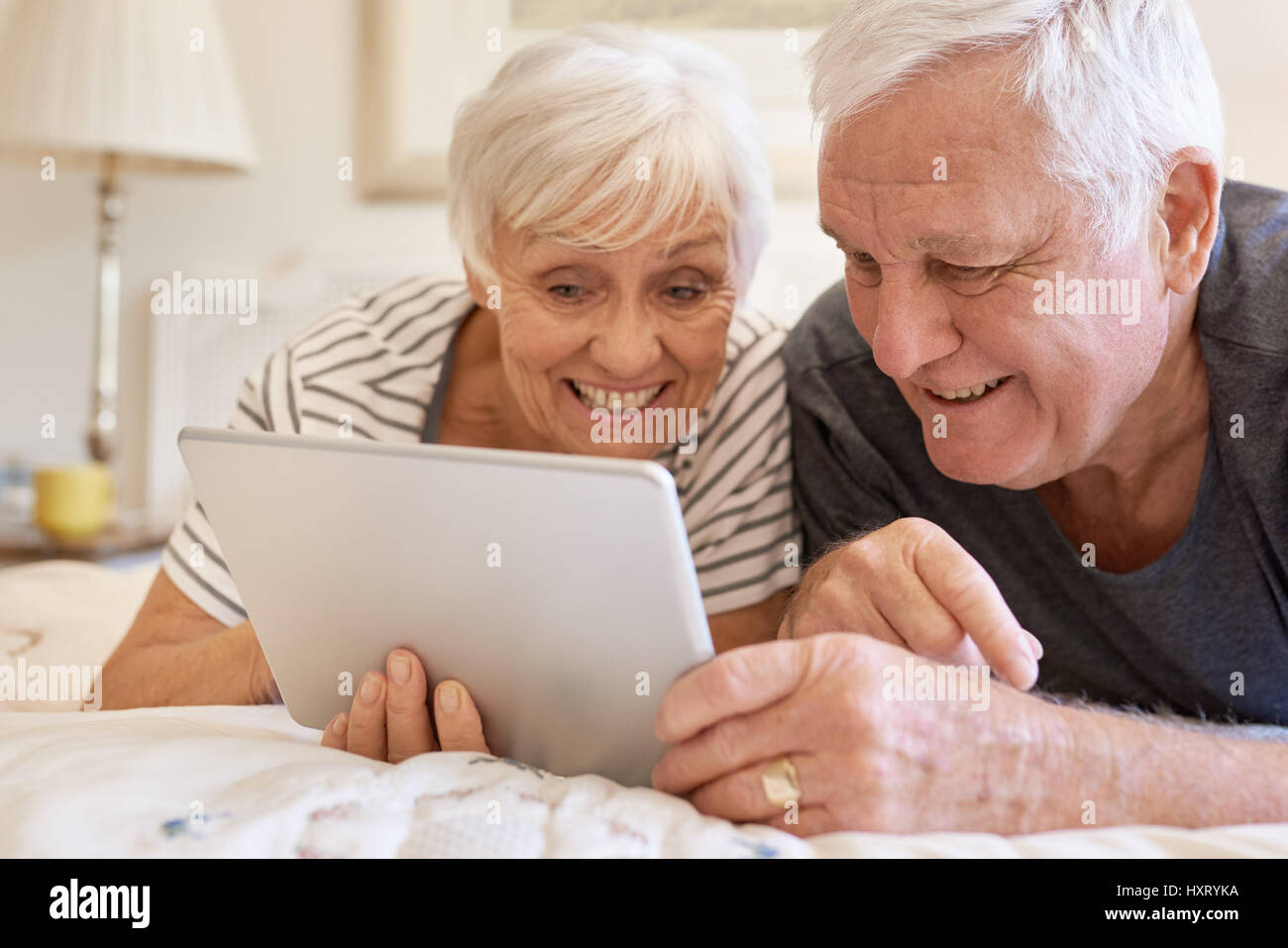 Smiling senior couple using a digital tablet together in bed Stock Photo