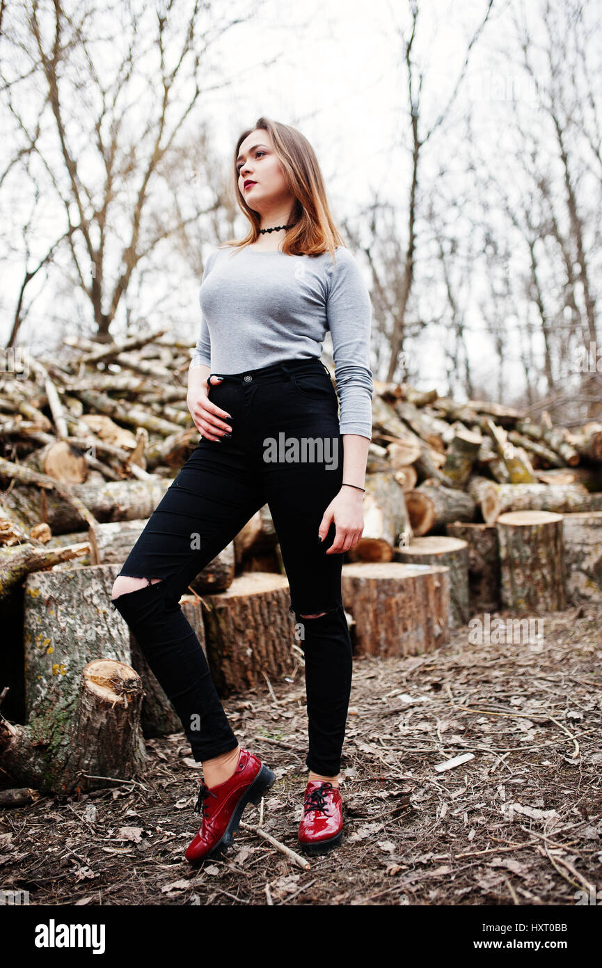 young hipster girl wear on black ripped jeans against wooden stumps HXT0BB