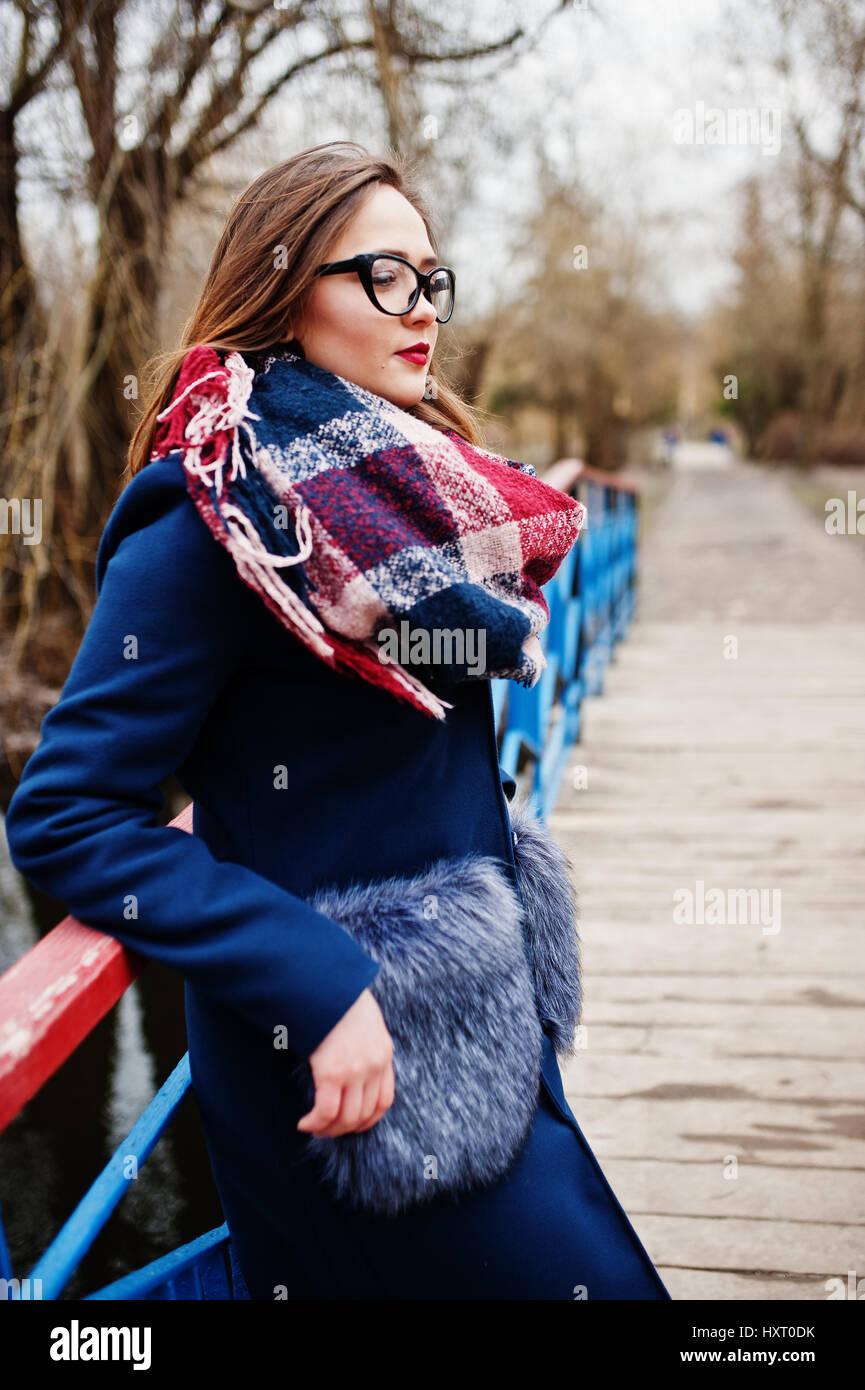 Young hipster girl wear on coat,scarf and glasses stay on small bridge at  early spring park Stock Photo - Alamy
