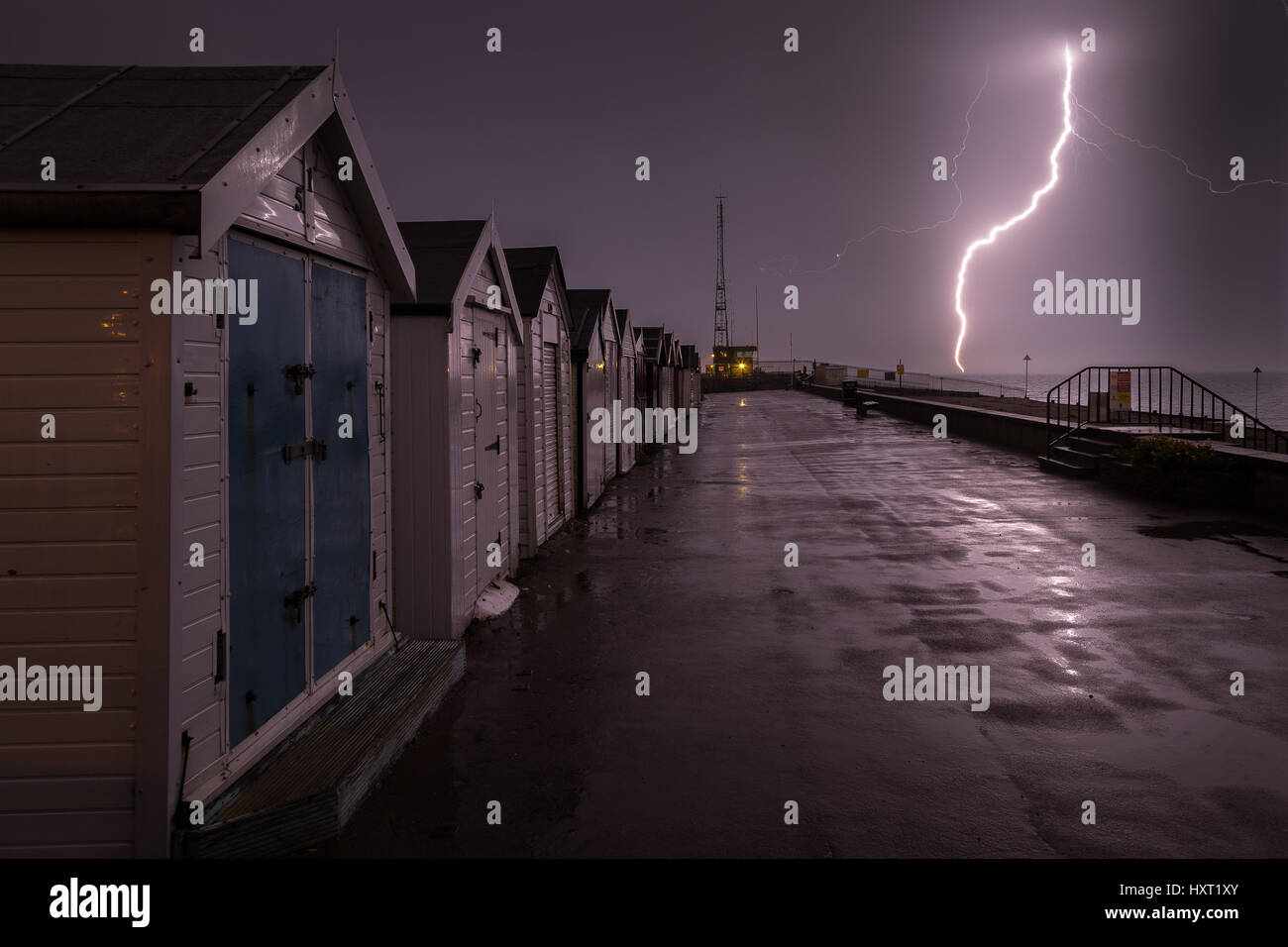 Lightning strike near beach huts and southend on sea coast guard tower, Essex, England Stock Photo