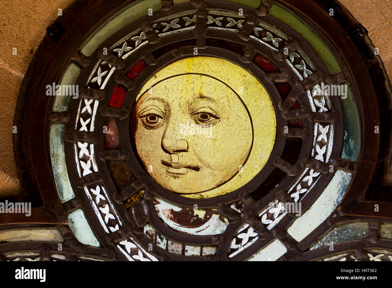 Medieval stained glass of a moon with a face, in the south porch, St. Mary`s Church, Burnham Deepdale, Norfolk, England, UK Stock Photo
