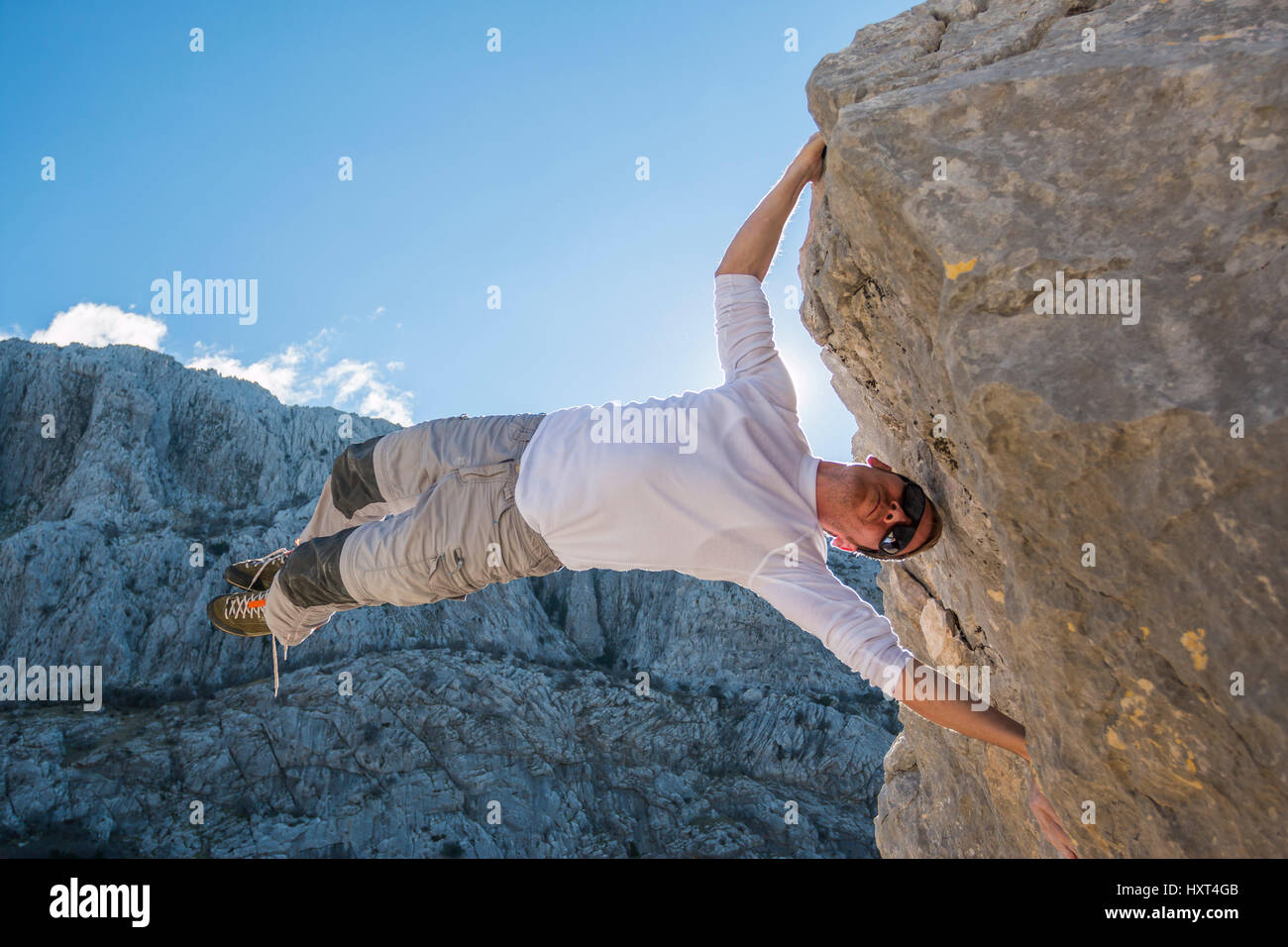 Young man climbing rock wall and hanging above gap. Roao, Villanueva del Rosario, Malaga Stock Photo