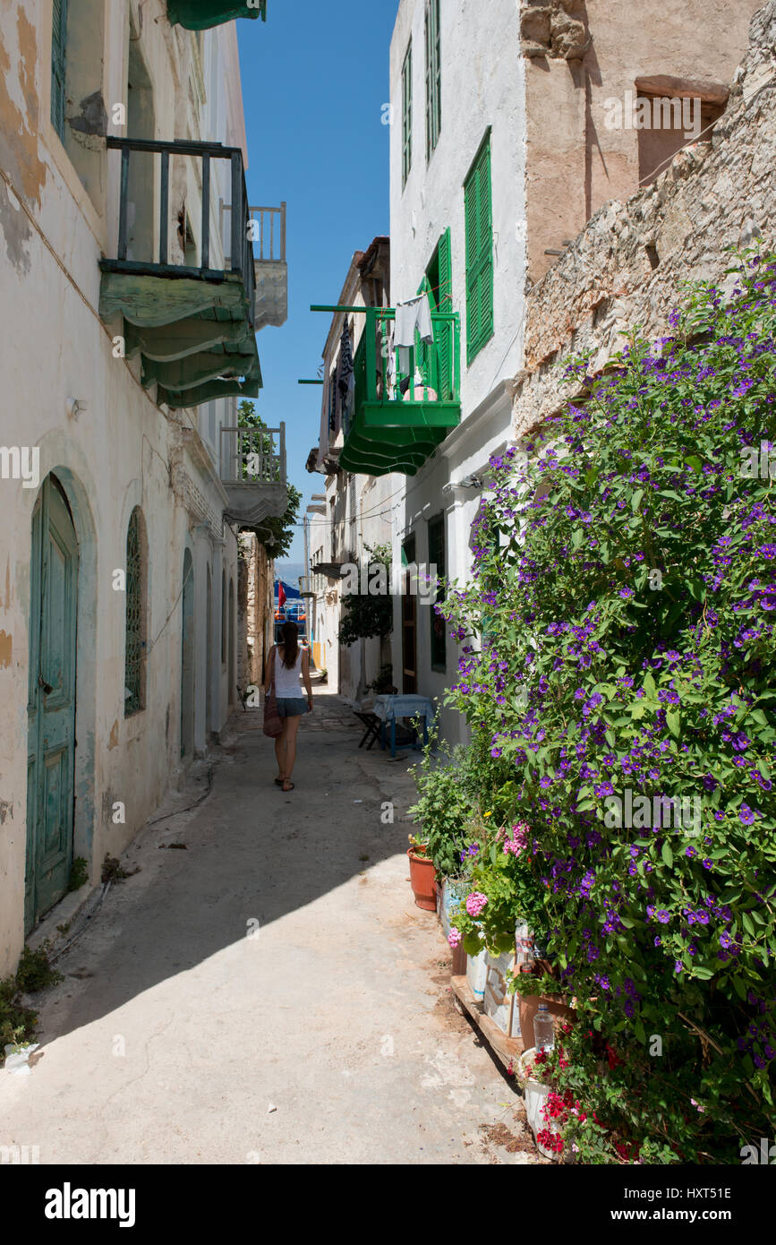 Mädchen geht durch enge schattige Gasse mit weißen Häusern mit grünen Balkonen, rechts Blumentöpfe, Insel Kastellorizo, Dodekanes, Griechenland Stock Photo
