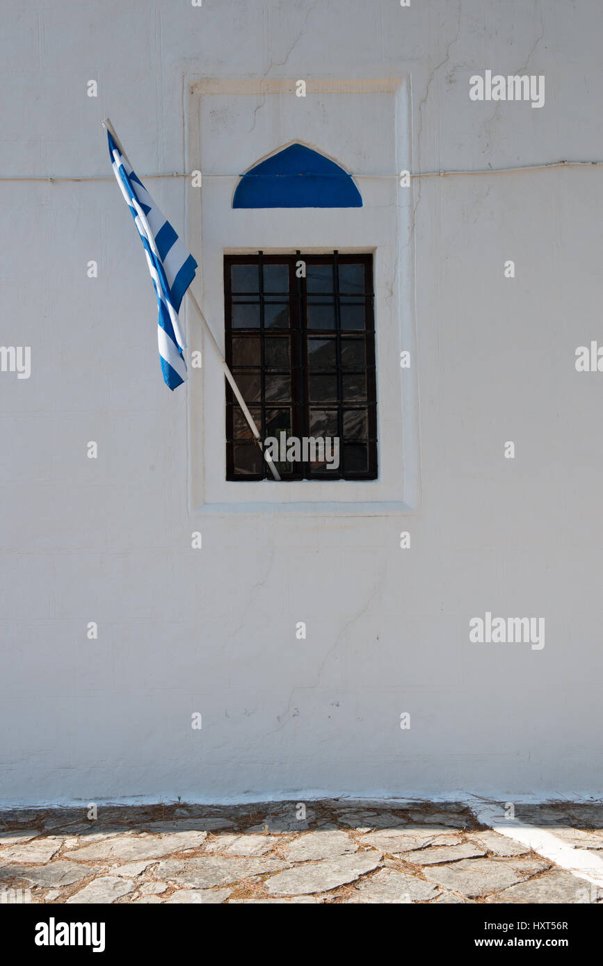 vergittertes Kirchenfenster in weißer Wand mit Spitzbogen in blau und griechischer Fahne, Insel Kastellorizo, Dodekanes, Griechenland Stock Photo