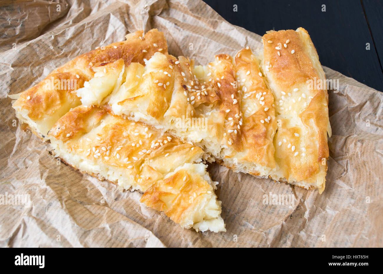 Cheese pie covered with sesame on wrapping paper Stock Photo