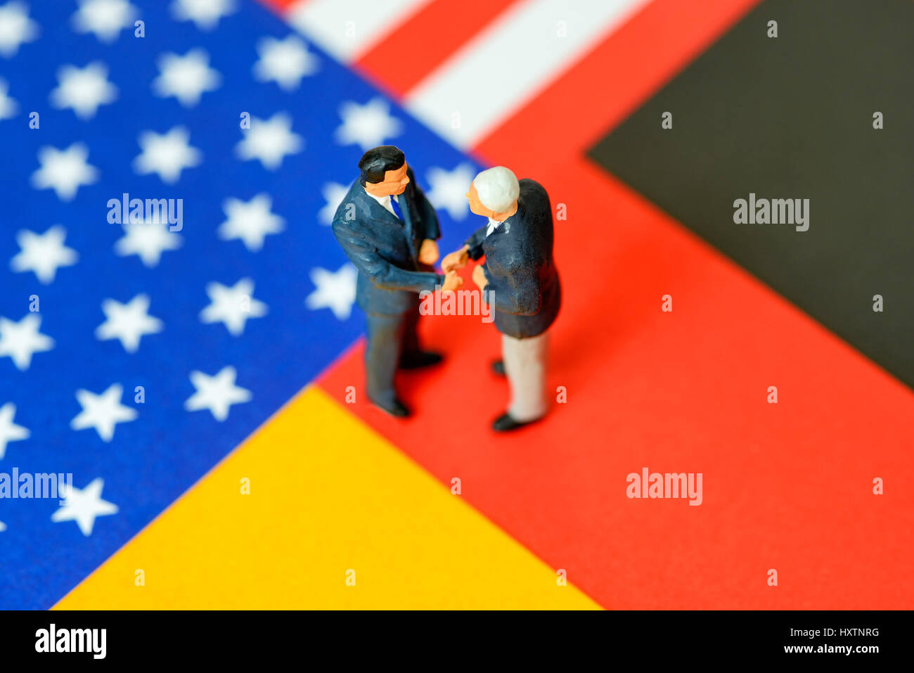 Slap of two miniature figures on the German and American flag, free trade agreement TTIP, Handschlag zweier Miniaturfiguren auf der deutschen und amer Stock Photo