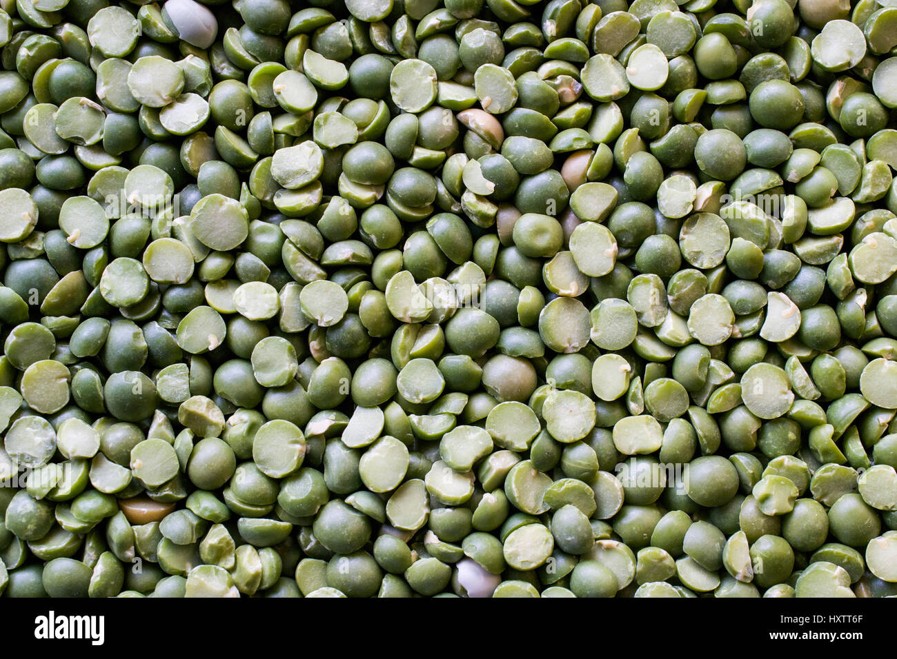 Unsorted green split peas background showing some broken, dried  and damaged peas that need to be weeded out before consuming - texture and background Stock Photo