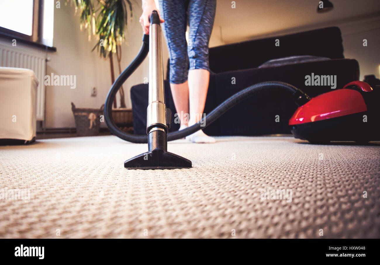 woman cleaning carpet with a vacuum cleaner in room Stock Photo - Alamy