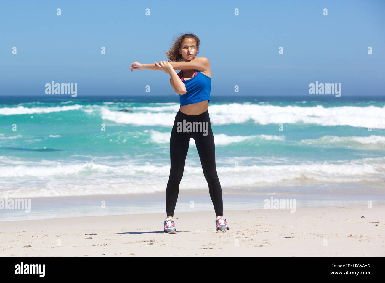 Full body portrait of fit young woman stretching at beach Stock Photo ...