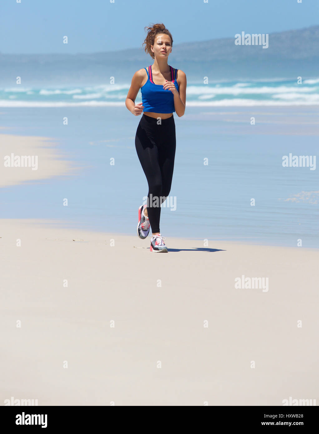 Full body portrait of a fit young smiling woman running on beach Stock ...